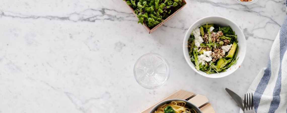 Flat lay of a nutritious meal with salad and pasta on a marble surface, perfect for healthy eating themes.