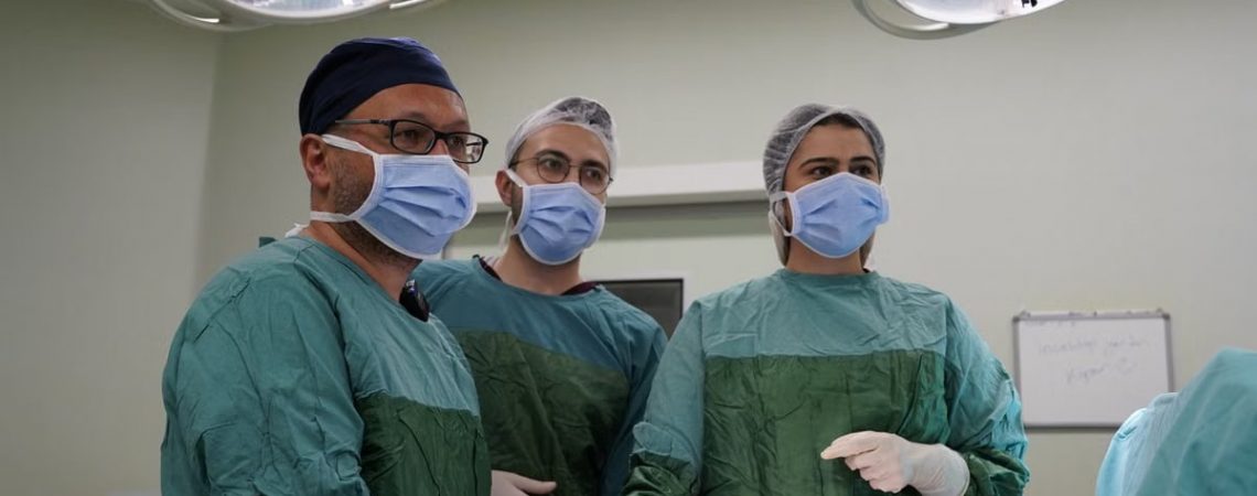 Surgeons focused in an operating room, wearing sterile attire, preparing for surgery.